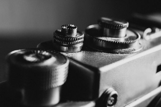 shutter button of an retro camera, black and white photo with noise