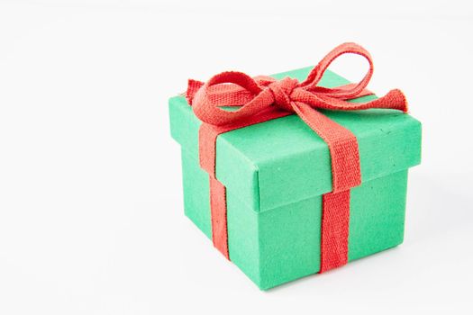 Present. Gift box with a bow. New Year's surprise. Red and green box with a gift. On a white background, top view. Close-up. Tied with a beautiful ribbon for gifting. Under the tree.