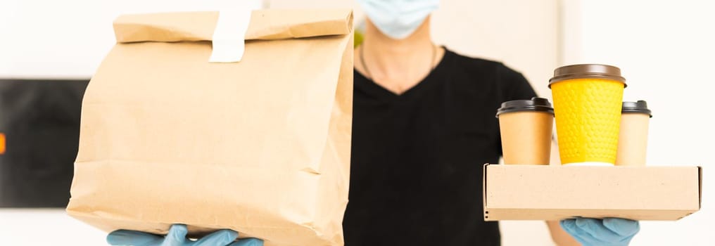 Delivery man holding cardboard boxes in medical rubber gloves and mask. copy space. Fast and free Delivery. Online shopping and Express delivery. Quarantine.