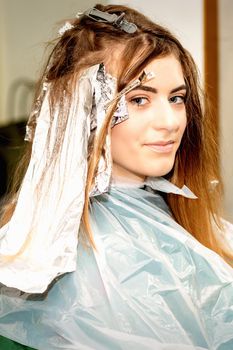 Portrait of a beautiful young caucasian woman getting foil on her hair before dyeing in a beauty salon