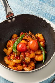 Shrimp casserole with tomatoes, garlic and peppers in black wok pan