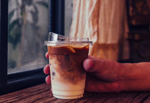 Hand hold iced latte coffee in a  tall glass. cold summer drink background