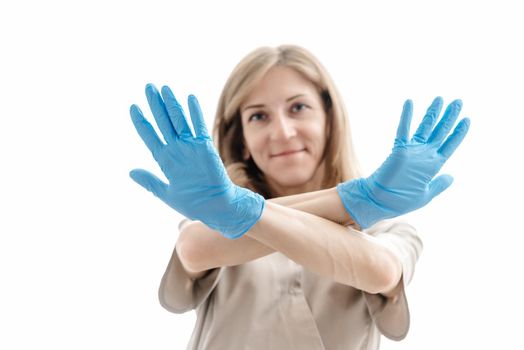 woman cosmetologist in uniform and blue latex gloves with arms crossed. White background. Concept of the health and beauty industry