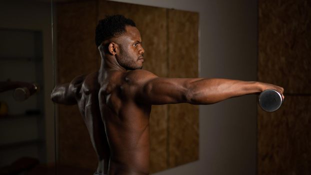 Attractive african american man doing arm exercises with dumbbells