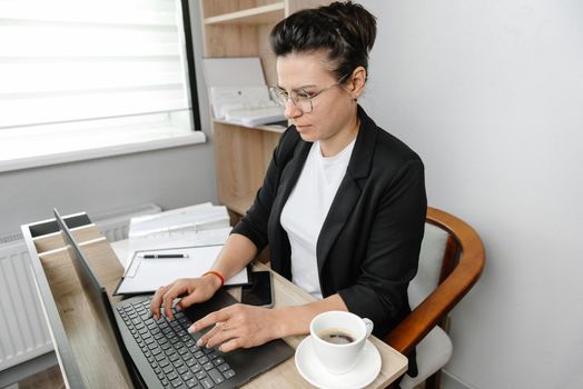 A young woman in the office working on her laptop. Real office