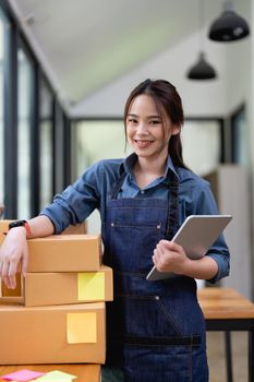Portrait of Asian young woman SME working with a box at home the workplace.start-up small business owner, small business entrepreneur SME or freelance business online and delivery concept