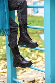 Slender female feets in military boots. street photo. woman wearing black jeans and blue scarf