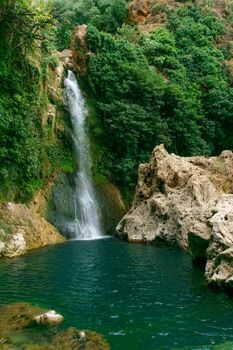 large waterfall over a natural pool for bathing with cold and crystalline water, silk effect, long exposure.