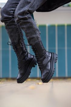 Slender female feets in military boots. street photo. woman wearing black jeans