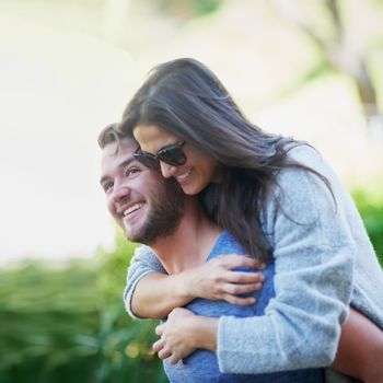 Happiest when theyre together. a young man giving his girlfriend a piggyback while enjoying a day together outside