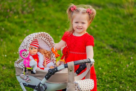 girl playing with a doll in a stroller in nature