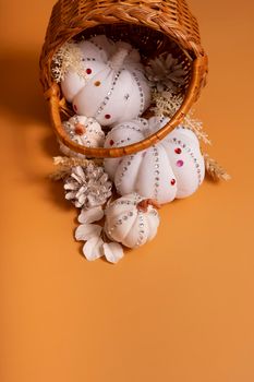 White decorative hand made pumpkins with shiny stones and pine cones in basket on colored background. Thanksgiving day concept.