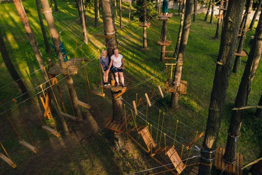 A girl passes an obstacle in a rope town. A girl in a forest rope park.