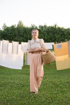 Laundry day. A woman hangs linen and towels on a tree in the courtyard of a village house. Summer cottage concept.