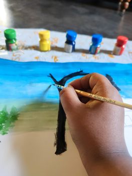 A child is painting in a paper. In the picture the painting is almost finished and the colors are at the top.