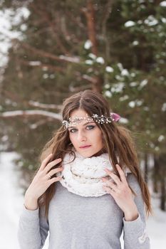 Beautiful bride in a white dress with a bouquet in a snow-covered winter forest. Portrait of the bride in nature.