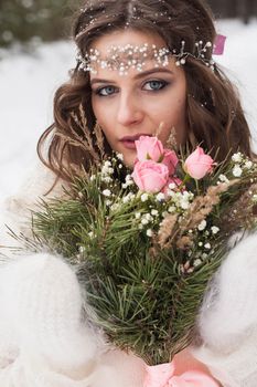 Beautiful bride in a white dress with a bouquet in a snow-covered winter forest. Portrait of the bride in nature.Beautiful bride in a white dress with a bouquet in a snow-covered winter forest. Portrait of the bride in nature.