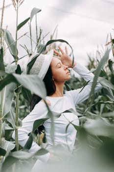 A brunette girl in a white dress in a cornfield. The concept of harvesting.