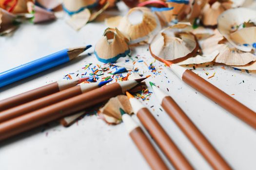 Wooden colorful pencils with sharpening shavings, on a white table