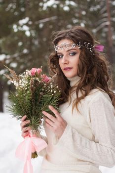 Beautiful bride in a white dress with a bouquet in a snow-covered winter forest. Portrait of the bride in nature.Beautiful bride in a white dress with a bouquet in a snow-covered winter forest. Portrait of the bride in nature.