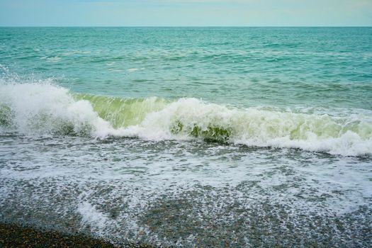 Sea shore with pebbles, wet sea pebbles on the beach and quiet sea surf. Restless sea and waves.