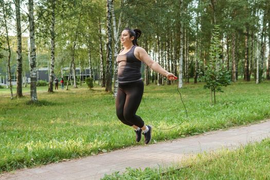 A charming brunette woman plus-size body positive practices sports in nature.