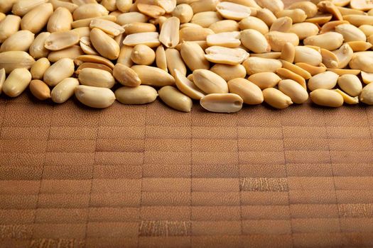 peeled peanuts seeds close up on  bamboo wooden background for copy space. (arachis hypogaea) Edible seeds. Healthy snack nutrition concept