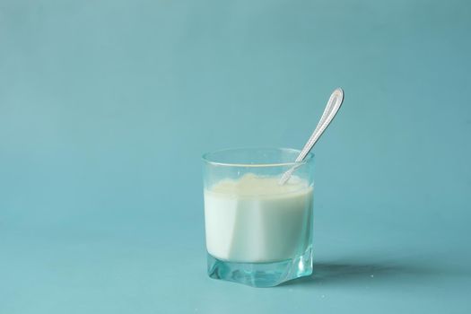 glass of milk and spoon on blue background ,