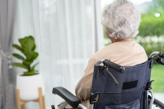 An elderly woman sitting on wheelchair looking out the window for waiting someone. Sadly, melancholy and depressed.