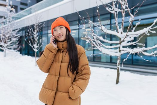 Excited happy Korean woman talking by mobile phone and laughing, she heard good news. Portrait of cheerful asian hipster holding smartphone