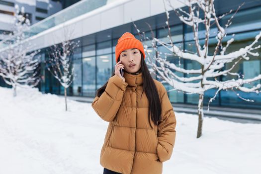 Excited happy Korean woman talking by mobile phone and laughing, she heard good news. Portrait of cheerful asian hipster holding smartphone