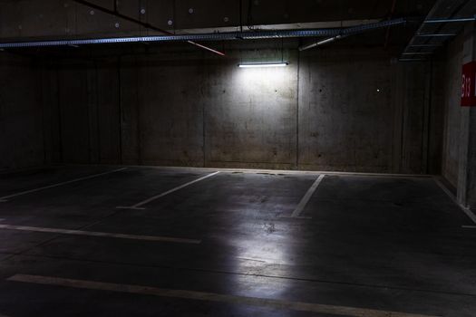 Empty parking lot with overhead dim light, underground parking garage.