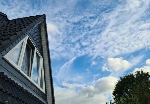 Open roof window in velux style with black roof tiles