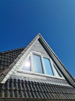 Open roof window in velux style with black roof tiles