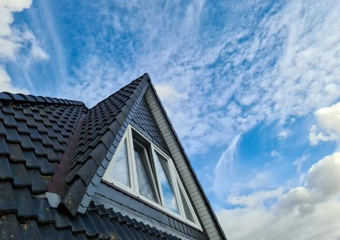 Open roof window in velux style with black roof tiles