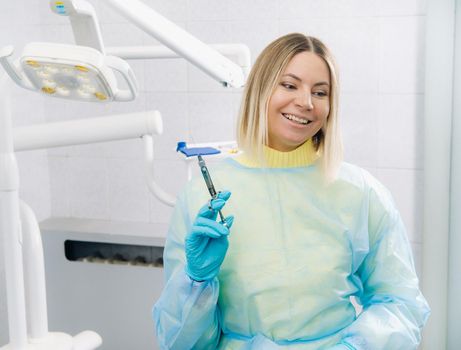 The dentist holds an injection syringe for the patient in the office.