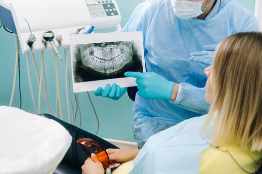 Dentist explaining the details of the X-ray to his patient in the office.