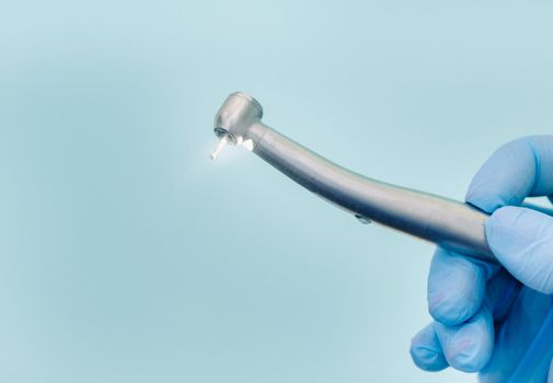 a dentist wearing gloves in the dental office holds a tool before working.