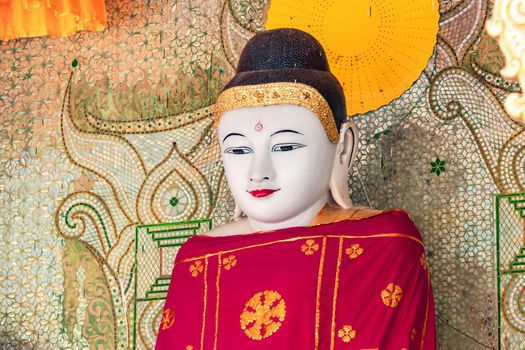 A large Buddha figure in front of a mosaic in the Shwedagon Pagoda at Rangon in Myanmar