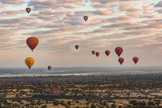 Many hot air balloons rise over the temple complex of Pagan in Myanmar at sunrise
