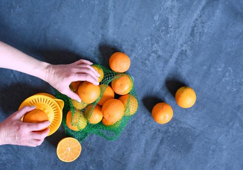 female hands make juice from oranges using a manual juicer, Orange on a blue background, summer dessert on a hot day, vitamin color drink, flatlay oranges. High quality photo