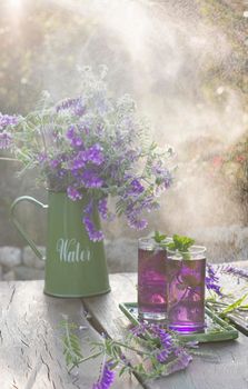 Lilac Lemonade of basil and mint, vintage still life purple and green, in the rays of the setting sun