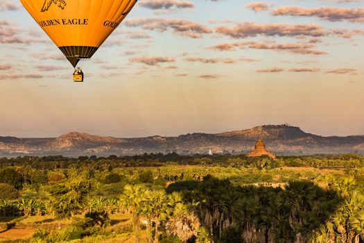 A hot air balloon at sunrise over the fields of the Bagan World Heritage Site in Myanmar