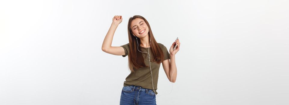 Portrait of a cheerful cute woman listening music in headphones and dancing isolated on a white background