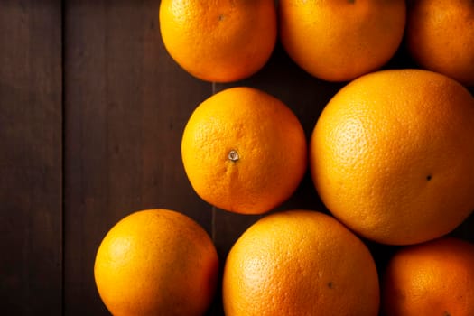 top view image of several whole oranges on broun rustic wooden table with copy space