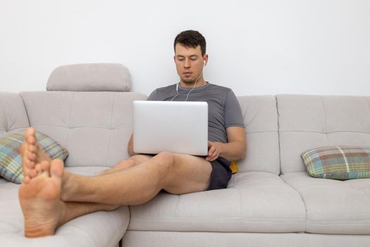 young man with laptop sitting on sofa with legs. High quality photo