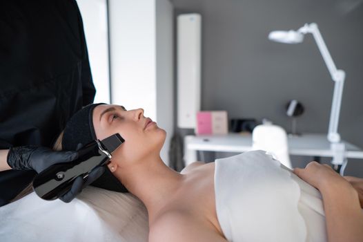 Woman on ultrasonic cleaning procedure. Hardware cosmetology