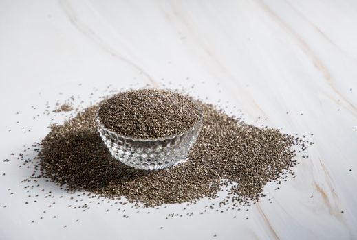 chia seeds in a cup and scattered around the table, abundance, ingredient. High quality photo