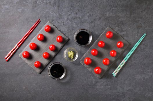 concept of a Japanese meal, cherry tomatoes instead of rolls, on a dark background, geometry, High quality photo