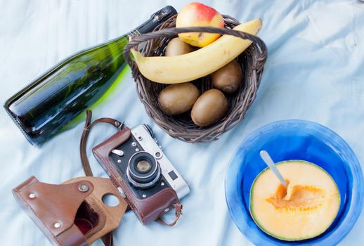 picnic in the garden or park on the green grass, plates and baskets with fresh fruits, champagne and retro photo camera. High quality photo